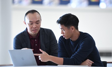 Student with career consultant checking on industry information on laptop