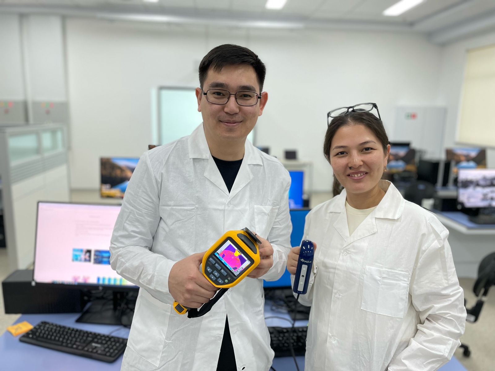 Nazarbayev University research fellows Dr Olzhas Mukhmetov and Dr Aigerim Mashekova, posing with an infrared temperature thermometer gun, which would be used with PINN that analyses heat patterns within the tissue, flagging any possible malignant tumours