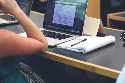 Woman attending a lecture with a laptop and notebook