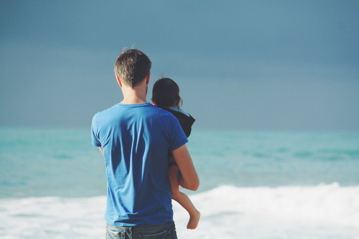 Man holding toddler and looking at the sea