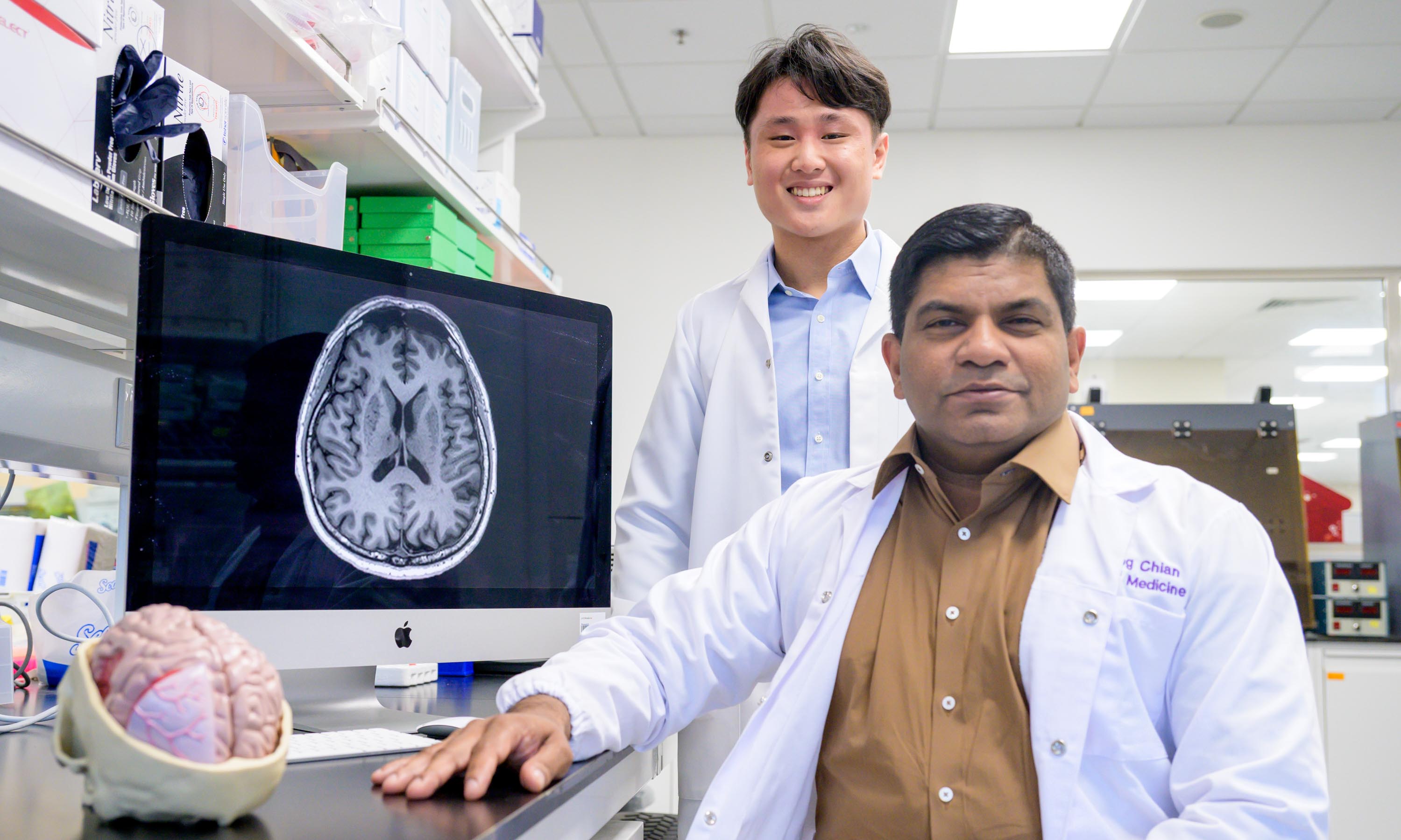 Associate Professor Nagaendran Kandiah and Justin Ong with a MRI image of a brain