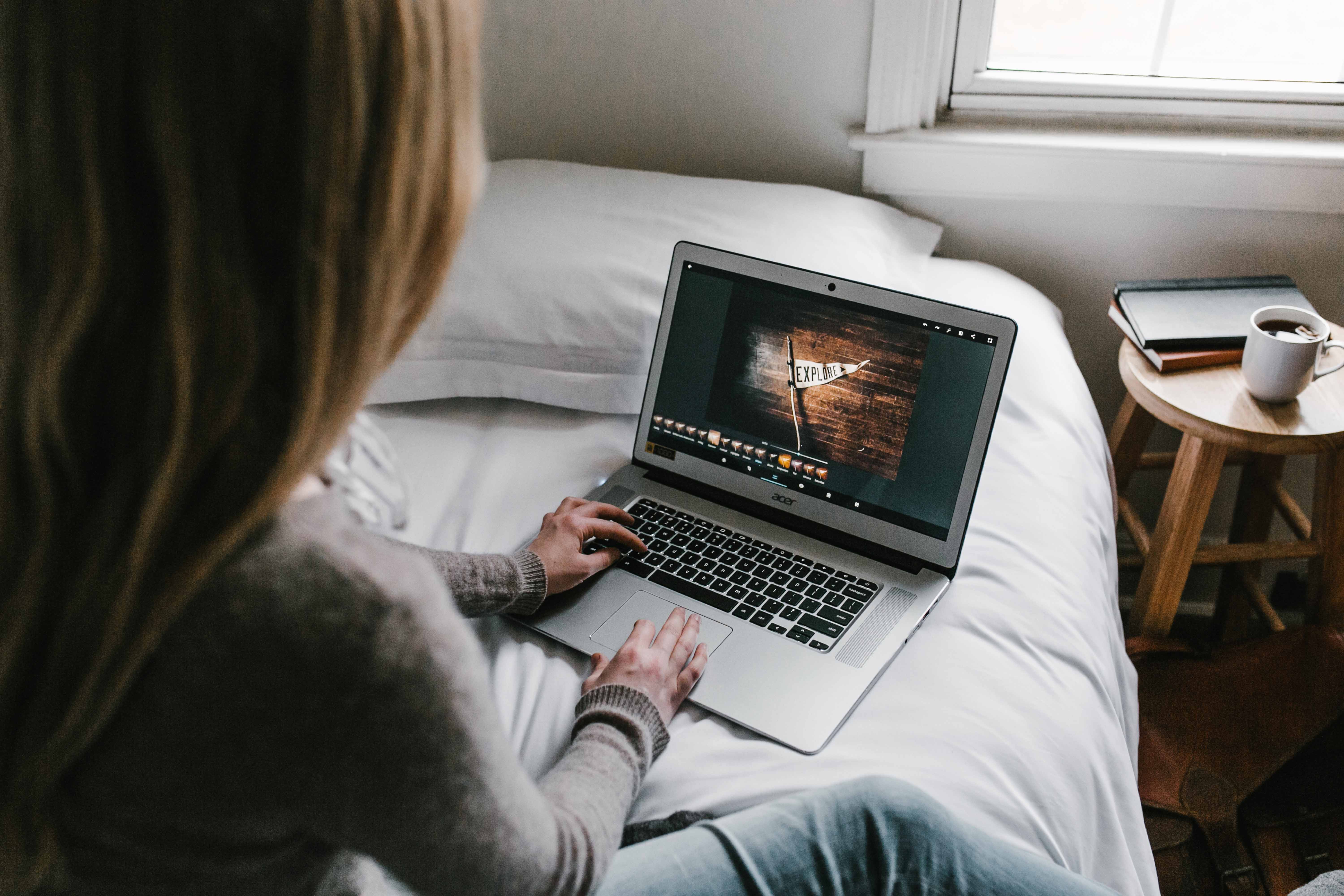 Woman using a laptop on a bed