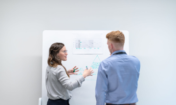 Two people discussing some accounting research findings, while writing on a flip chart