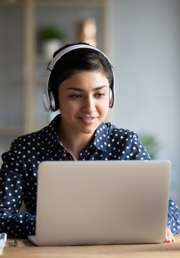 Woman looking at laptop wearing headphones