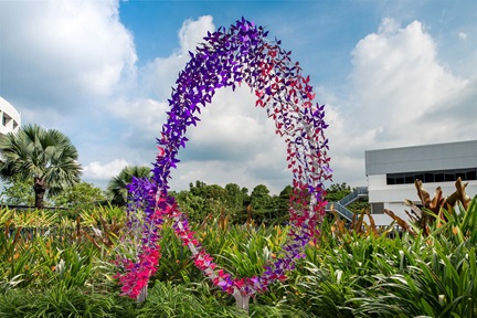 Sculpture of pink and purple butterflies in a mobius loop against the backdrop of blue skies and greenery