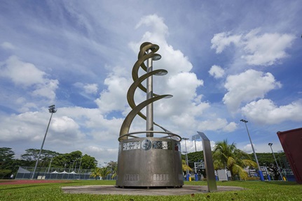 Spiralling stainless steel sculpture against backdrop of blue sky on sunny day