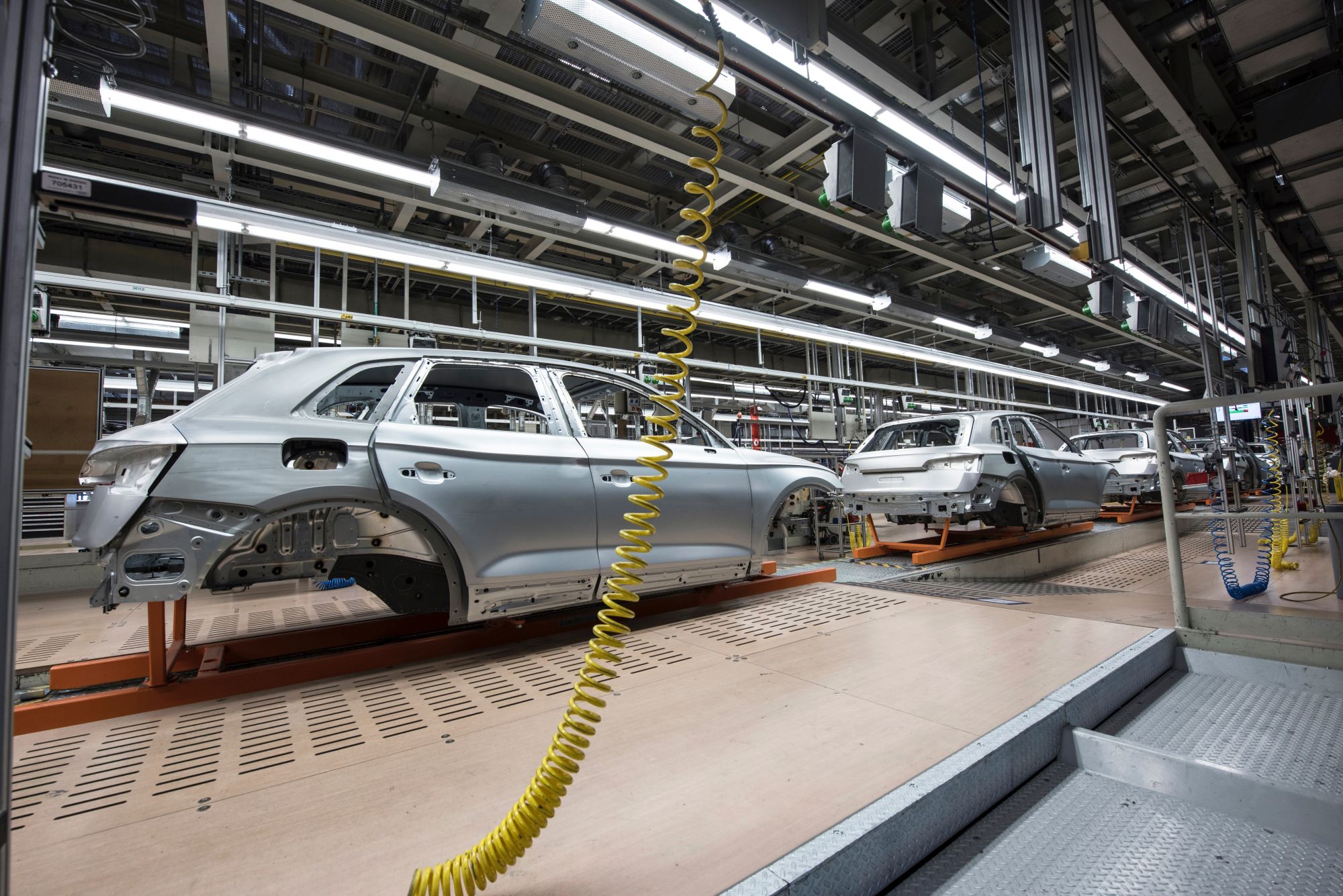 White sedans being assembled in a factory.