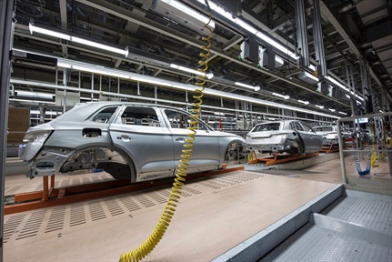White sedans being assembled in a factory.