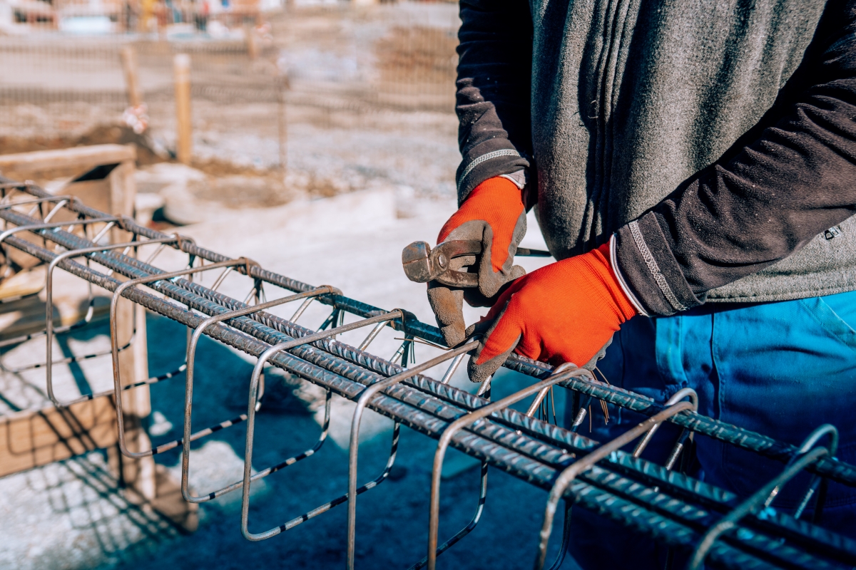 Details of construction worker - hands securing steel bars with wire rod for reinforcement of concrete or cement