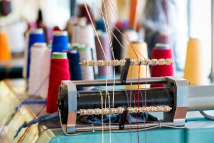 Yarn feeder with threaded wool of assorted colors on knitting machine at a knitwear factory