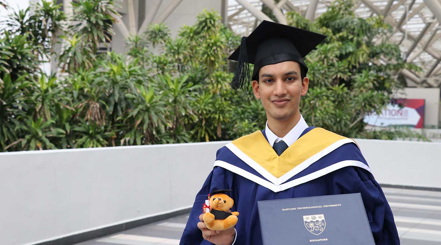 Photo of an undergraduate holding a toy bear and a graduation certificate.