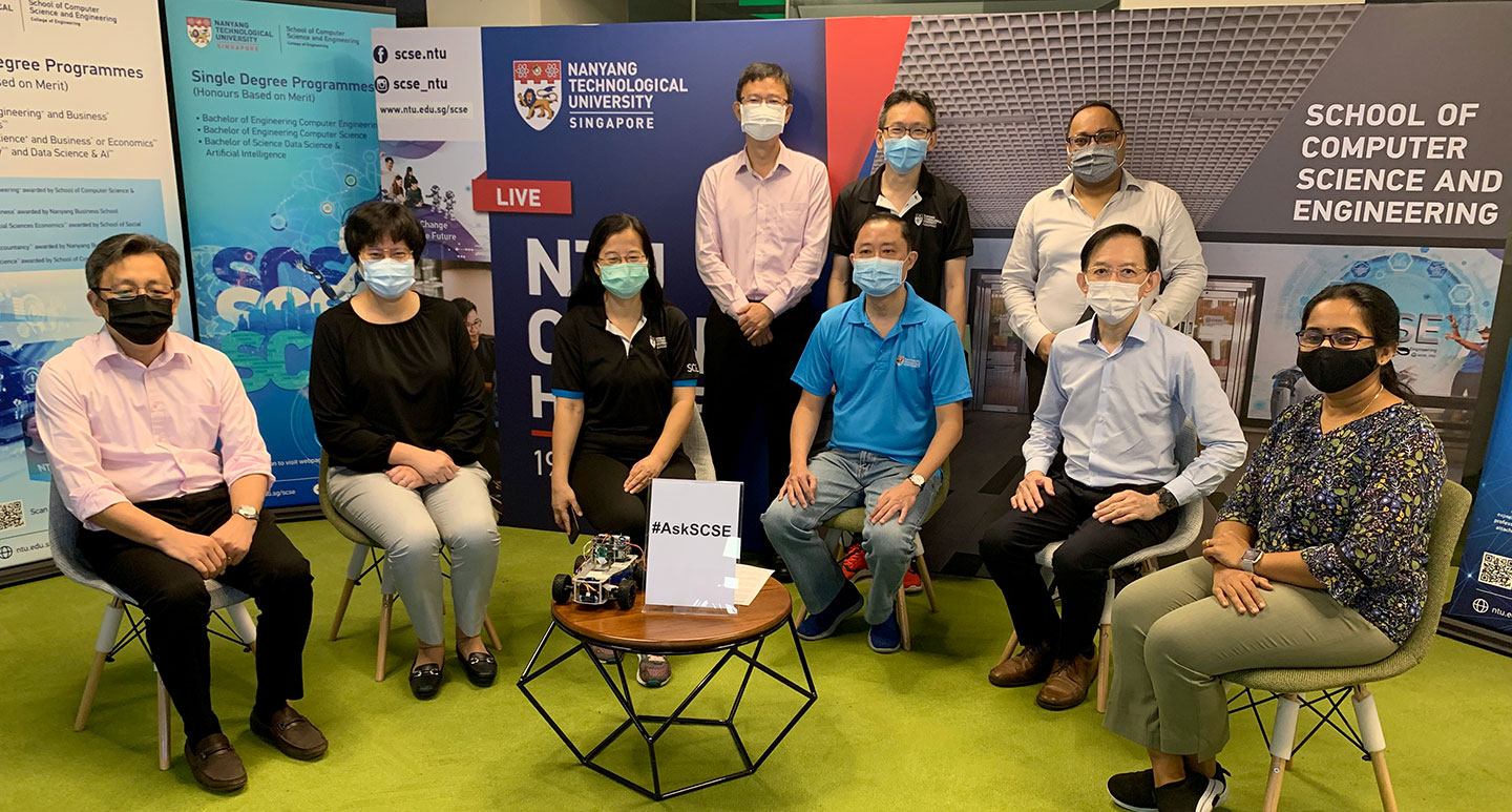 A group photo of 6 faculty sitting and 3 standing before the Open House backdrop.