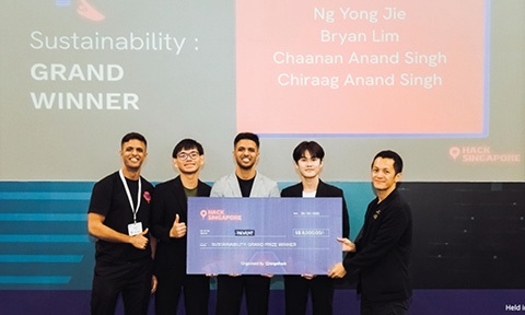 Photo of 4 undergraduates receiving grand prize with cheque board on stage.