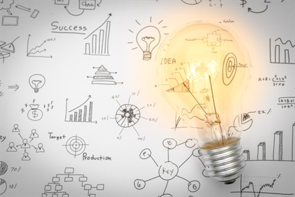 Light bulb glows on paper of analytics and sketches