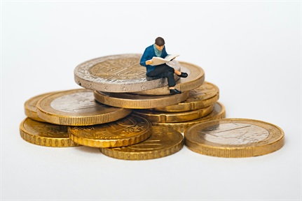 Miniature figure sits on a pile of gold coins British pound