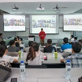 Speaker dressed in a red hoodie, sharing his ideas and presentation to students in a classroom