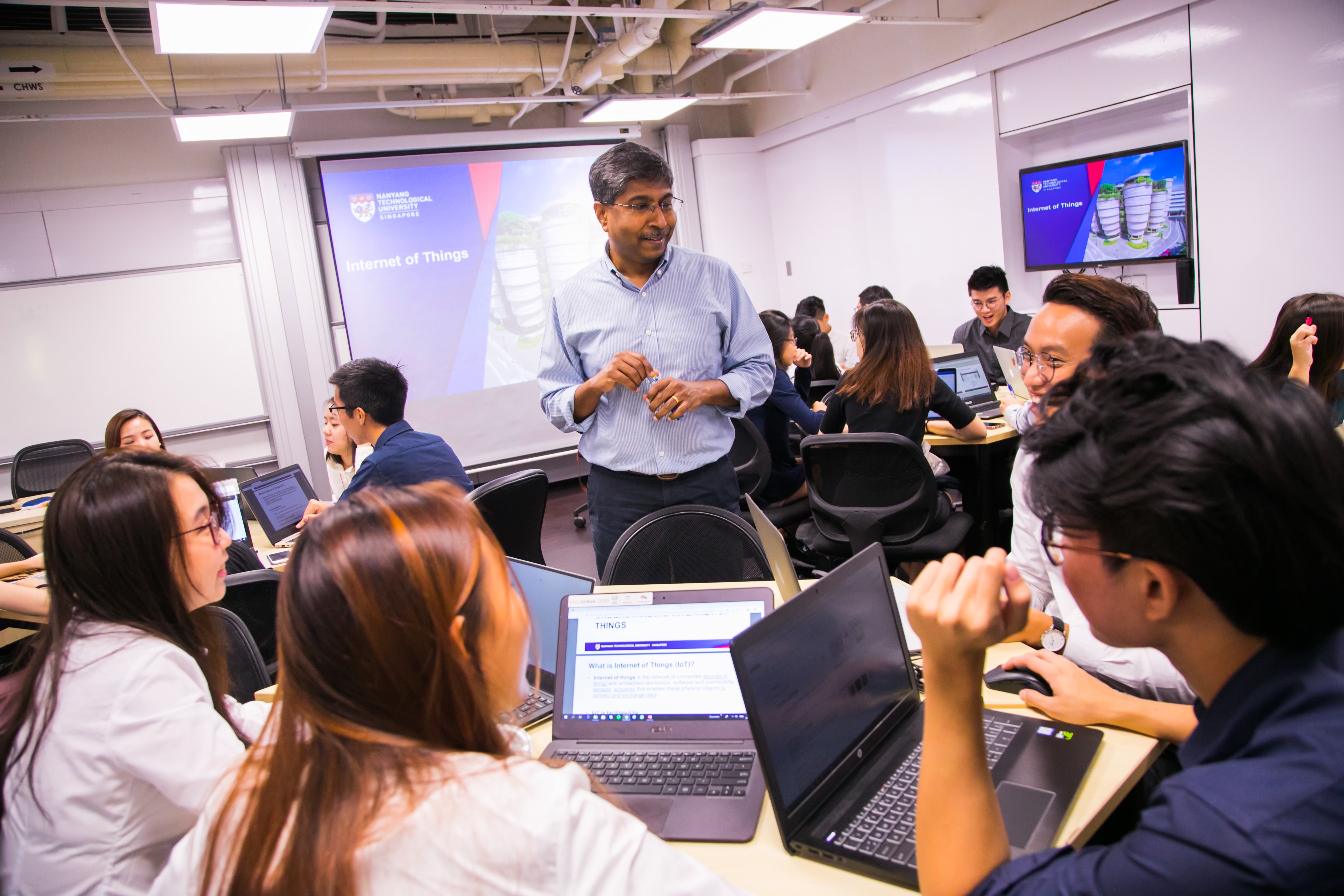 Students around a table in discussion with professor in class