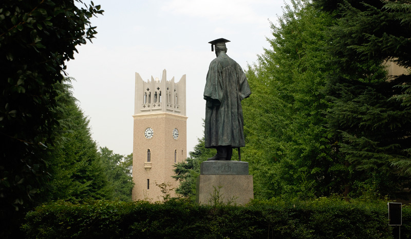 A statue of a university scholar, overlooking a school clock tower