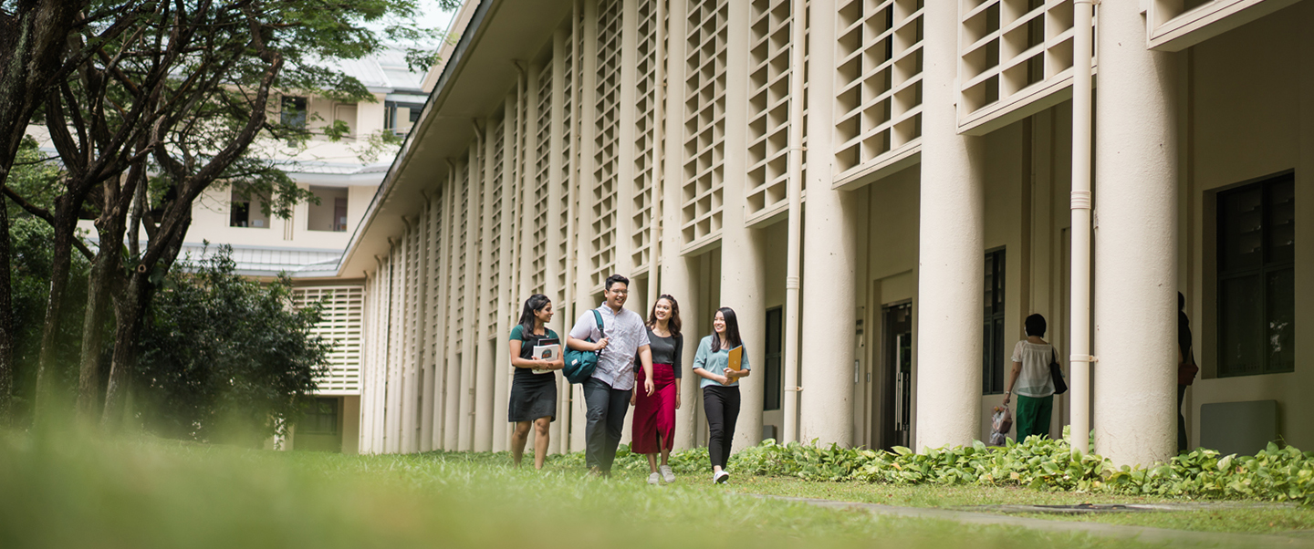 Longshot Of A Group Of 4 Students Walking In NIE Campus On A Grassy Path