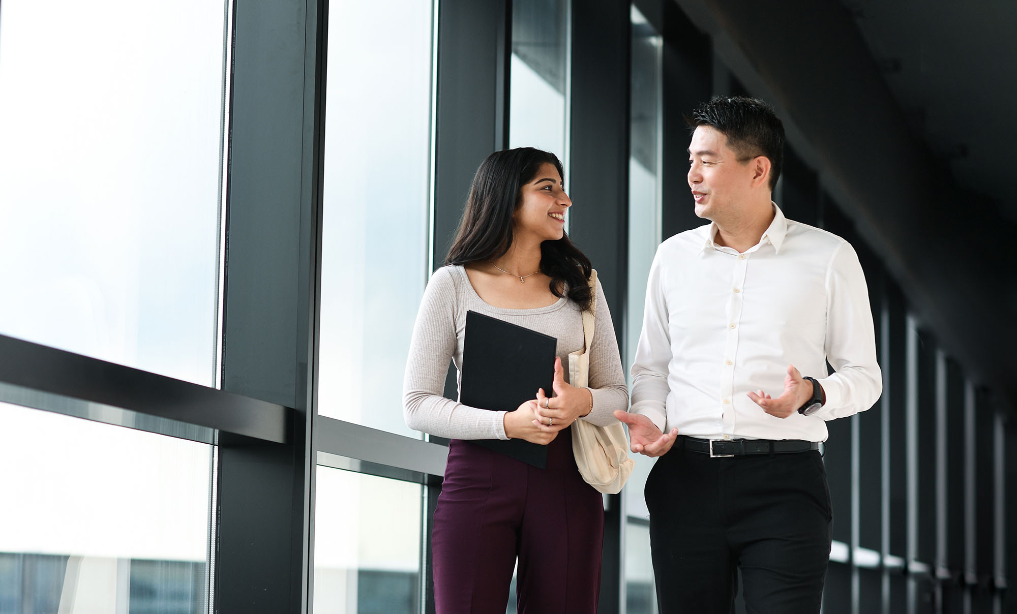 NTU student in conversation with a mentor while walking along a campus corridor