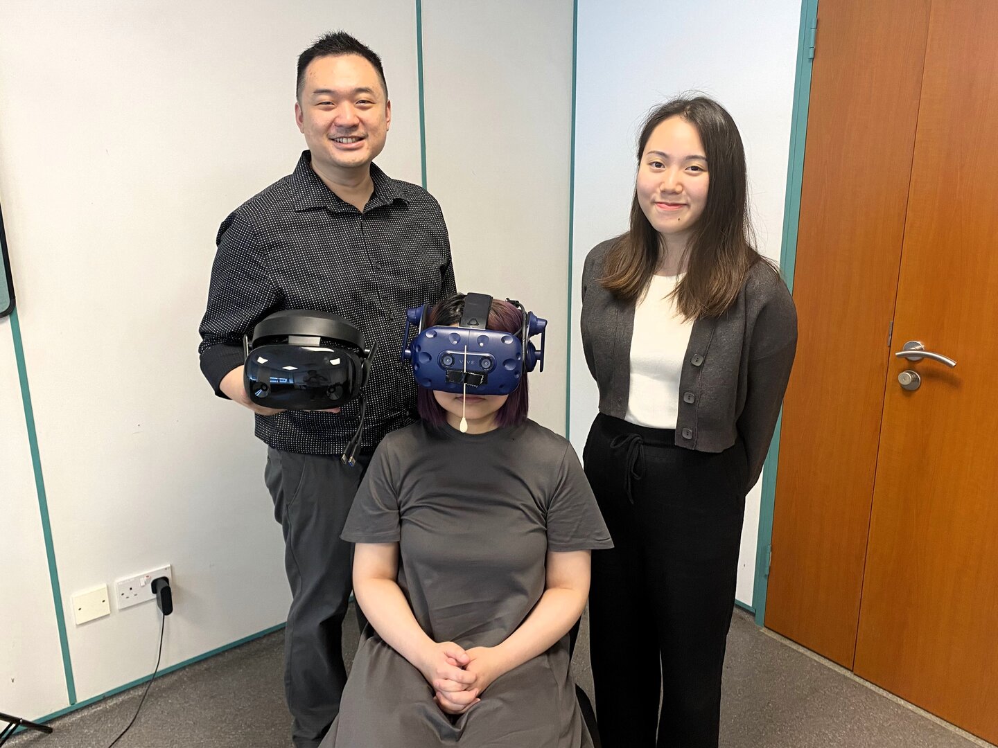 NTU’s Wee Kim Wee School of Communication Assistant Professor Benjamin Li Junting, who led the study, and co-author of the study, NTU’s WKWSCI master’s student Ms Lee Hui Min, posing with a subject equipped with a VR headset