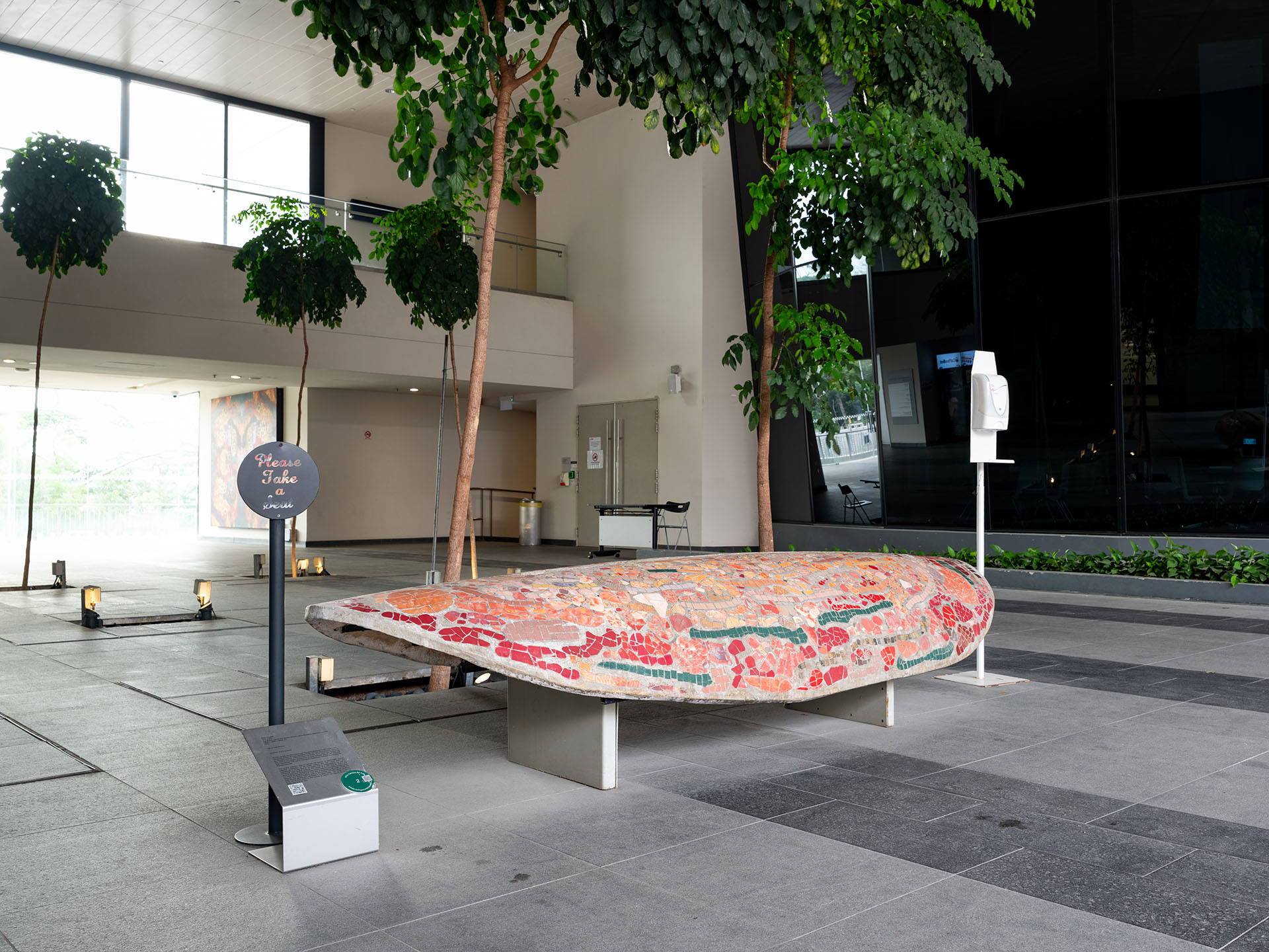 Angled view of red stone bench in an atrium with trees