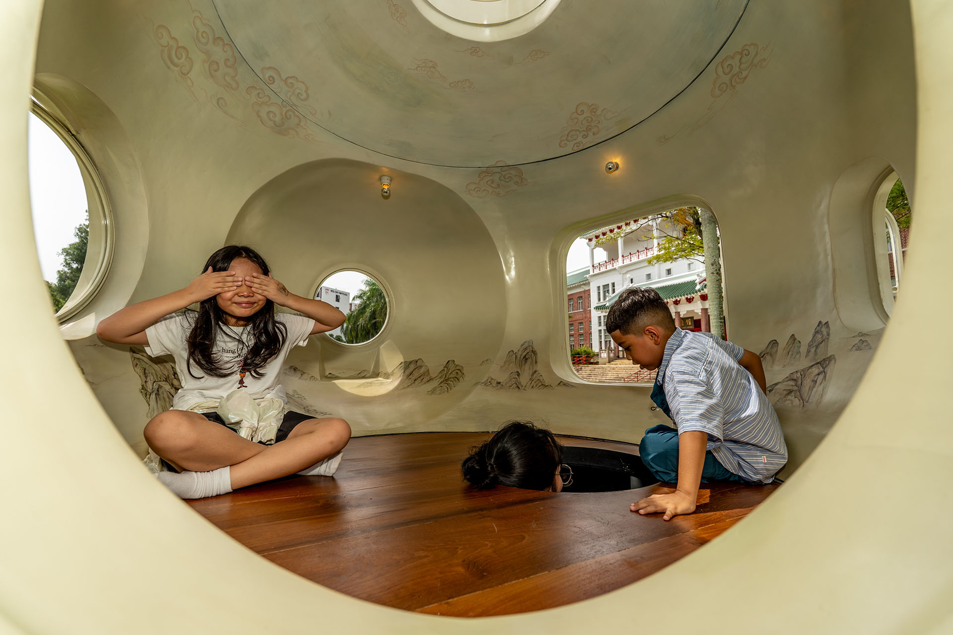 Two children in a white structure with round openings