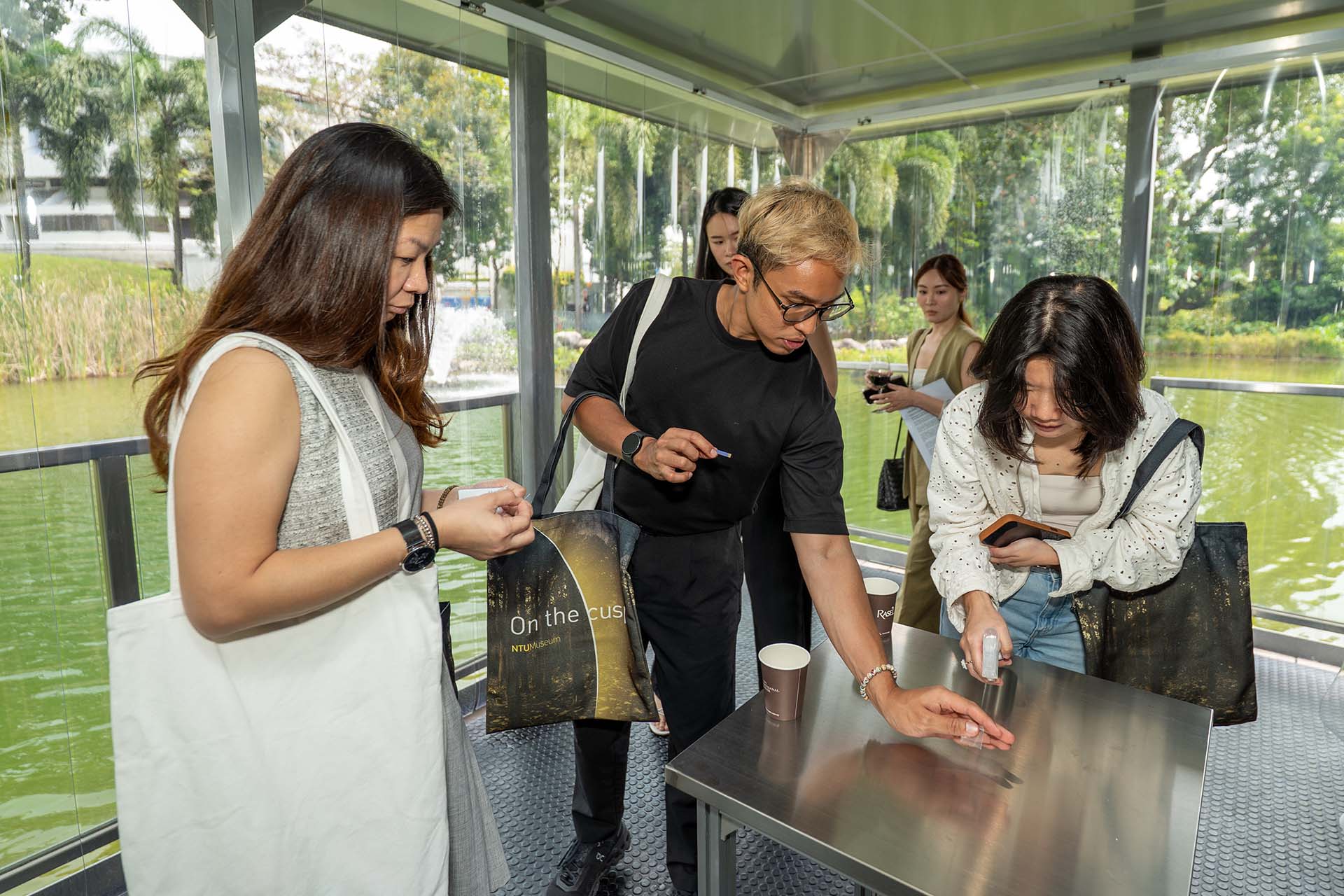 People curiously reaching out for a strip of paper on a metal table