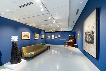 Wide view of gallery with artwork on walls and a couch