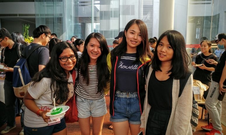 Four freshmen taking a group photo at a tea reception.