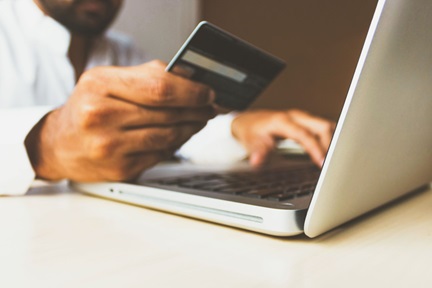 Person holding credit card and making e-payment on laptop.