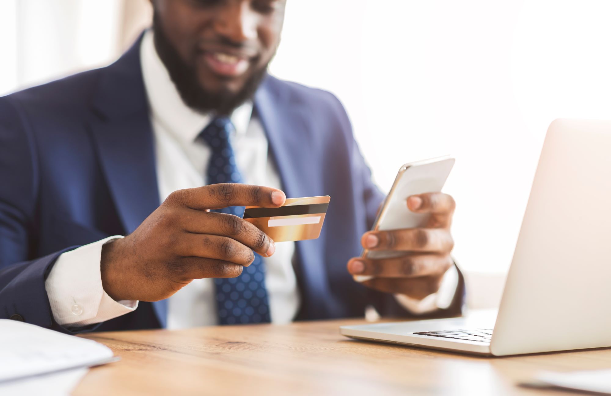 Businessman making payment, holding credit card and phone