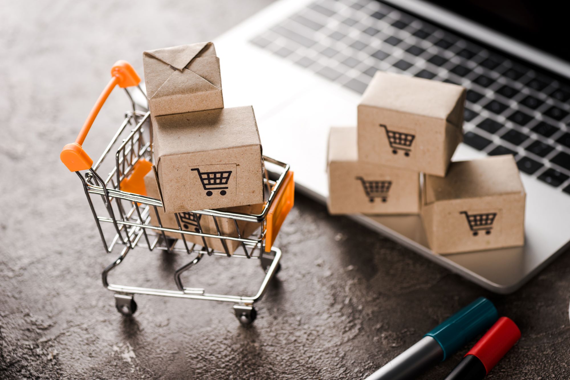 Shopping cart with small carton boxes near laptop