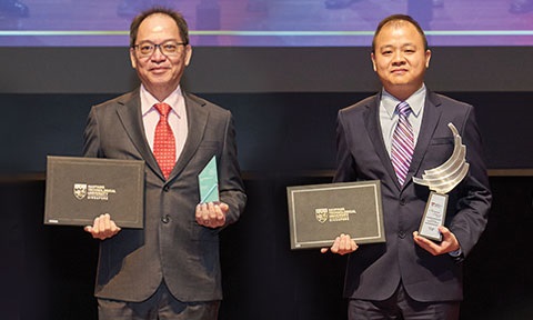 Thumbnail photo of 2 professors holding a cert and a plaque on each hand.