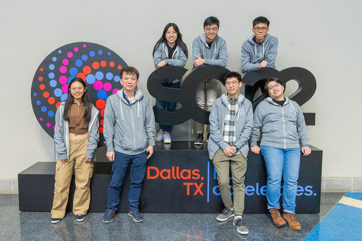 Group photo of 6 University students and a lecture standing beside the SC22 award prop.