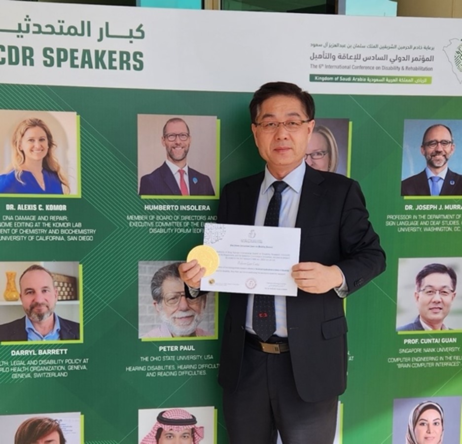 Photo of male Professor holding a cert and a medal.