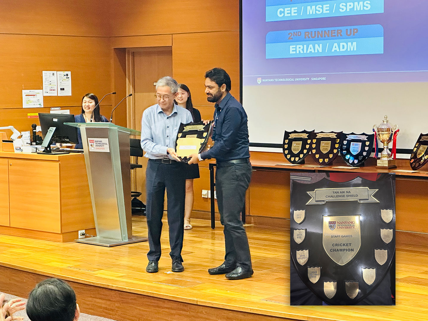 A staff receiving awarded plaque on stage.