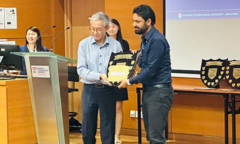 A staff receiving an awarded plaque on stage.