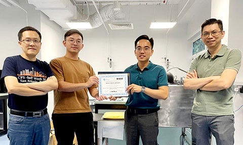 Photo of four awardees, two researchers at the center holding a Best Paper Award.