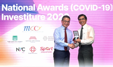 Photo of a Professor is receiving an awarded medal on stage.