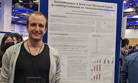 Thumbnail photo of a postgraduate student standing beside a poster of his project.