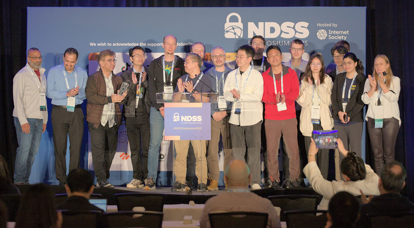Photo of a group of researchers at NDSS conference on stage.