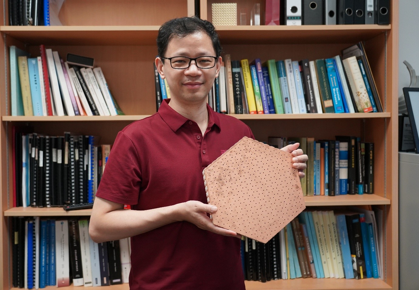 Professor Baile Zhang with the photonic axion insulator, which guides electromagnetic waves along its hinges in a zigzag network.