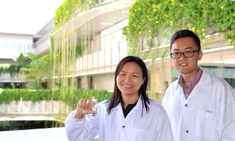 Prof and researcher hold up bottle containing samples of printed skin