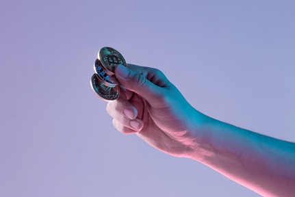 Hand holding out three metal coins bitcoin purple light