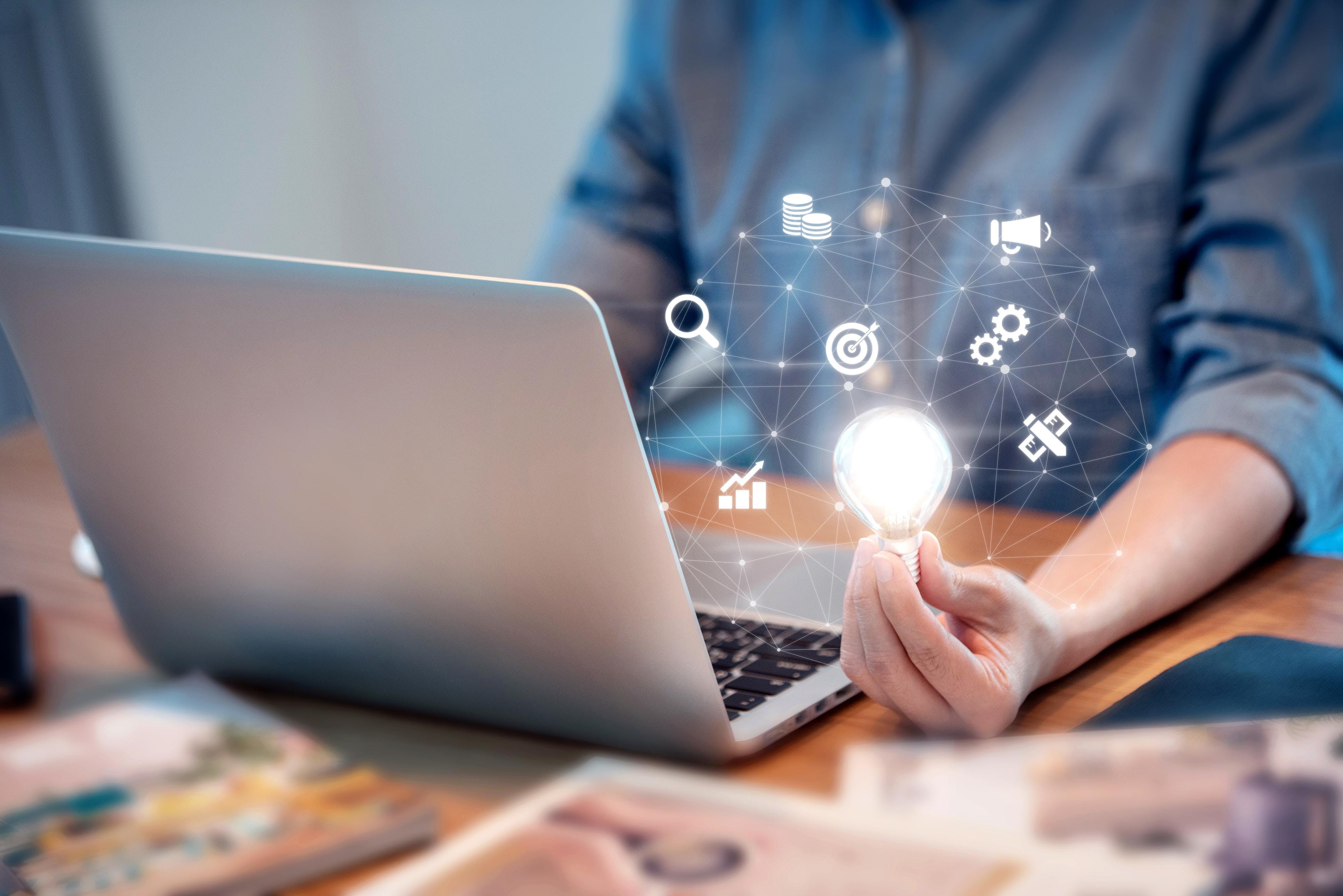 Business student holding a lightbulb typing on a laptop presentation pitch