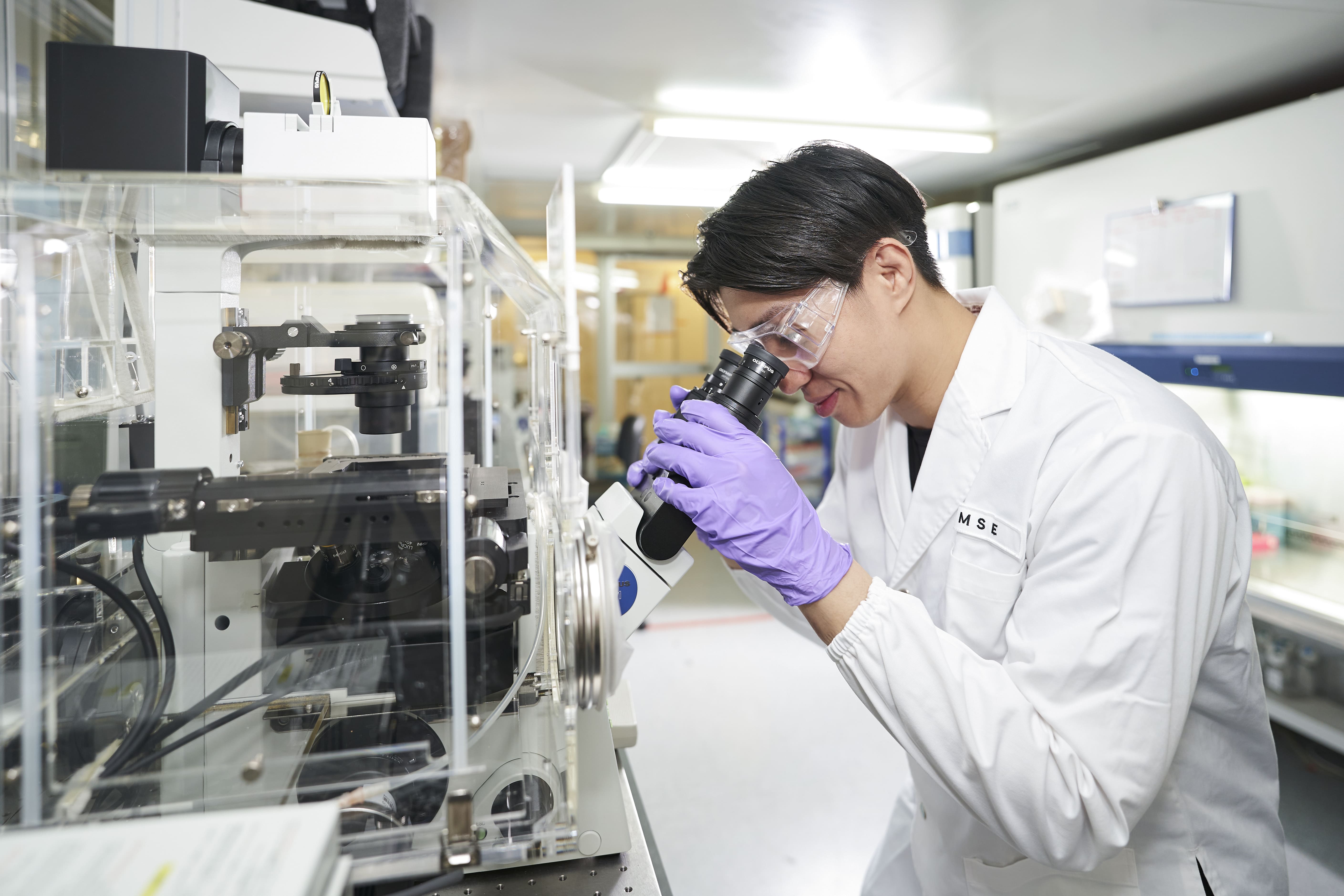 Student observing a sample through a microscope in a lab