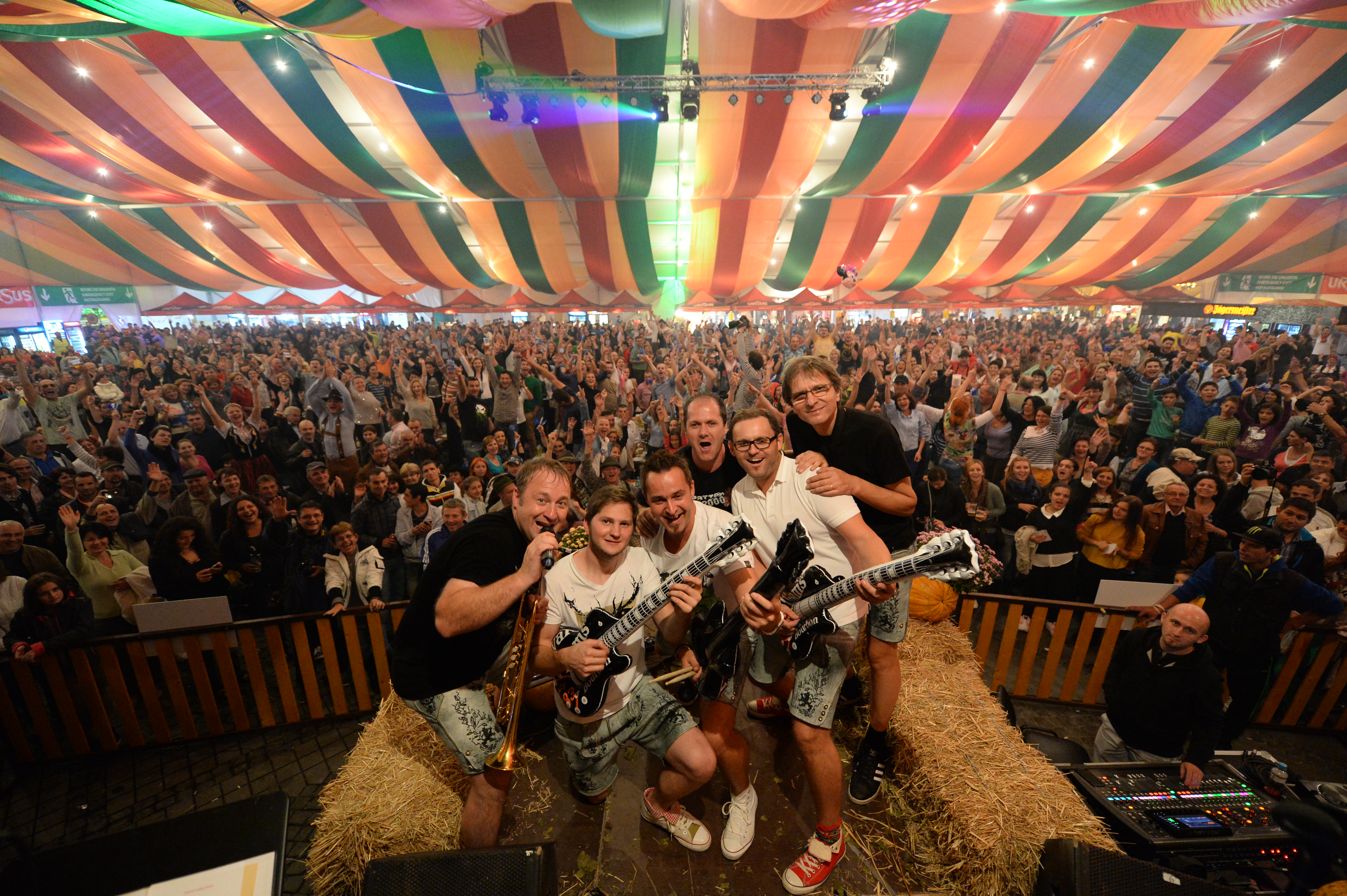 A band performs to a packed festival tent, the crowd on its feet with arms raised