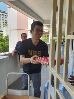 NBS Alumni Association exco member Ko Yang distributing essential food items to residents in the Hoy Fatt areas