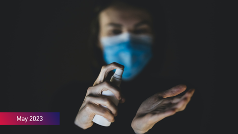 A man wearing a face mask using a hand sanitiser with the text May 2023 on the image